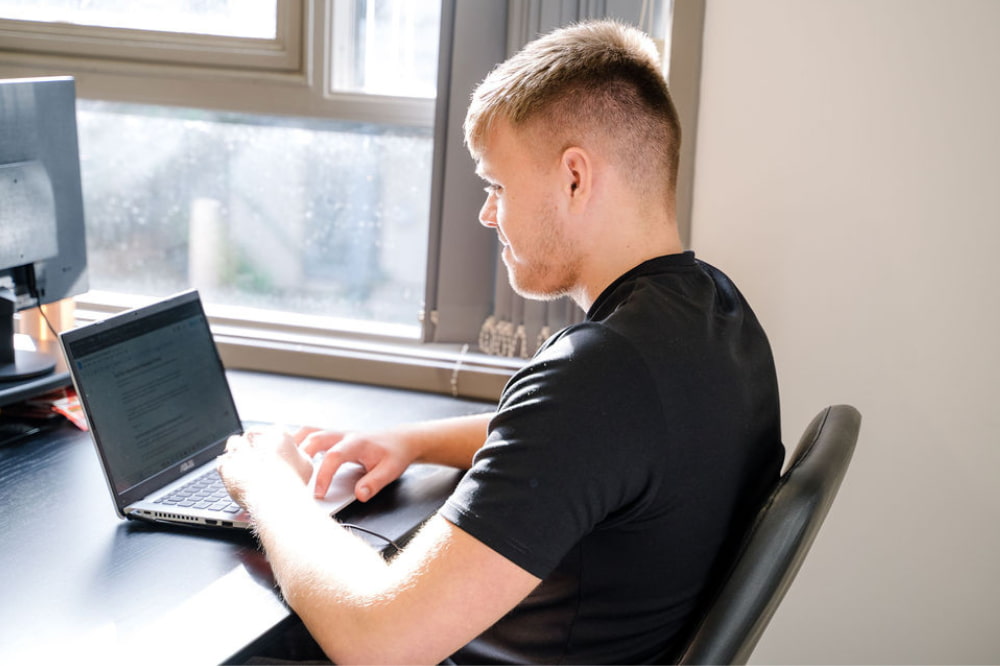 A man wearing a black t-shirt is researching the top digital PR trends in 2024 to increase his brand awareness and SEO efforts in the online environment.