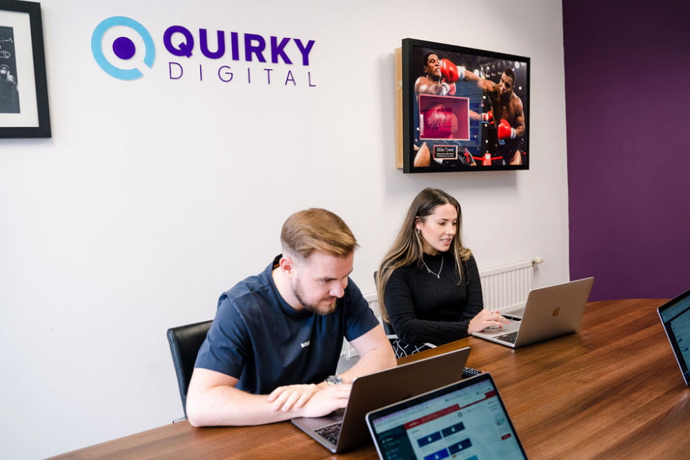 A picture of the Quirky Digital meeting room with the logo in the background.